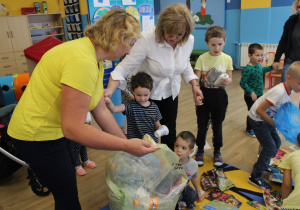 Przedszkolaki segregują śmieci do odpowiednich worków.